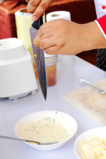 Thai chef is pressing lemon juice along knife into banana cream