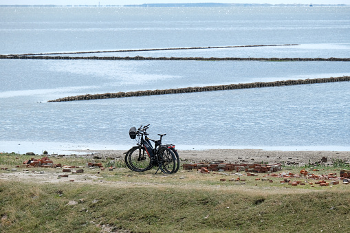 Excursion and cycling concept at the coast: Two electric bicycles on the beach of Rantum on the German North Sea island of Sylt with a view over the Wadden Sea