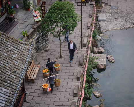 Hunan, China - Nov 6, 2015. Miao people sell fruits at Fenghuang Ancient Town in Hunan, China. Fenghuang is still be kept in its original appearance with 300 years passed.