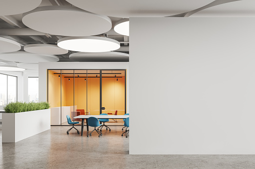Interior of modern office meeting room with white and yellow walls, concrete floor, long conference table with blue chairs and copy space wall on the right. 3d rendering