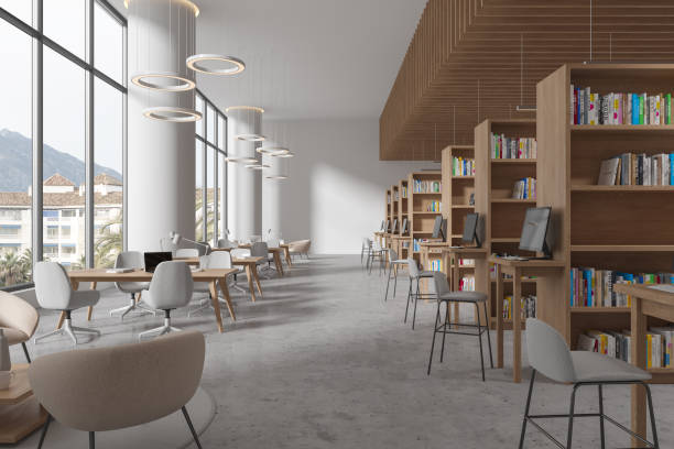 istock Stylish library interior with table and chairs in row, bookshelf and window 1614360538