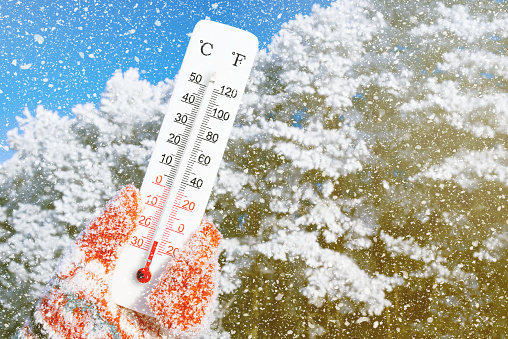 White celsius and fahrenheit scale thermometer in hand. Ambient temperature minus 25 degrees celsius