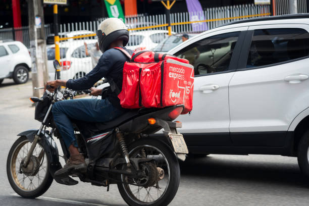 um entregador de comida de aplicativo é visto andando de moto na avenida bonoco entre carros - coffee sack bag espresso - fotografias e filmes do acervo
