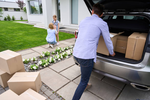 istock Man carries cardboard boxes with things from car to new house 1614375460