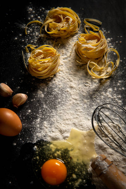 istock Freshly cooked pasta is lying on a dark surface dusted with flour. Italian pasta. Tagliatelle. Raw pasta. Italian pasta recipe. 1614391137