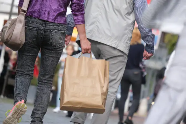 Young woman and elderly man and other people shopping in a shopping street or pedestrian zone with shopping bags, selective focus