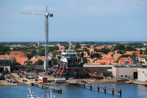 View of a dry dock in the harbor of Skagen, Denmark's northernmost town, with houses and the sea in the background