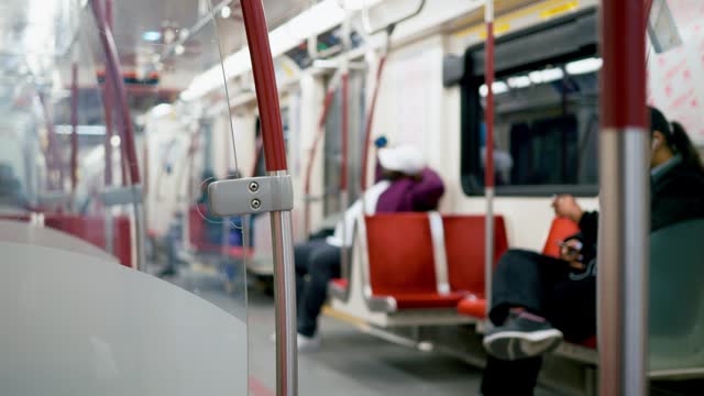 Defocused shot of passengers riding at night subway car. Dynamic video of calm passengers on red comfortable carriage seats near handrail. Concept night subway car riding fast to take passengers home