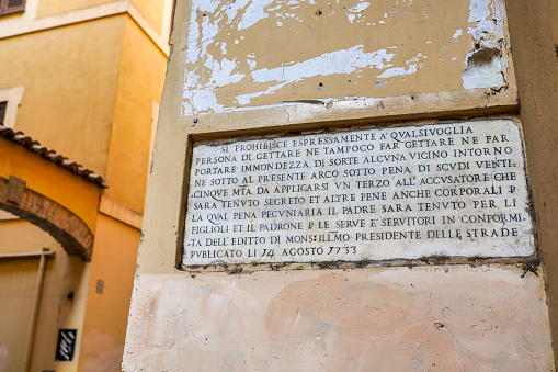 Rome, Italy, August 13 -- A marble warning plaque affixed in 1733 along via dei Cappellari, an alley in the Campo de Fiori district, in the heart of Rome. The peculiar text, written in Italian, forbids any person to throw rubbish along the alley, under penalty of paying five coins and even corporal punishment, according to the edict of the road manager issued on August 14, 1733. The Campo de Fiori district is an area of the Eternal City much loved and visited by tourists and residents for the presence of ancient churches and noble palaces and for the countless Renaissance and Baroque artistic and cultural treasures. Around Campo de Fiori, in the ancient Rione Parione (Parione district), you can explore dozens of characteristic alleys, with typical restaurants, pubs and pizzerias, where you can discover the essence and soul of Roman life. In 1980 the historic center of Rome was declared a World Heritage Site by Unesco. Image in high definition quality.