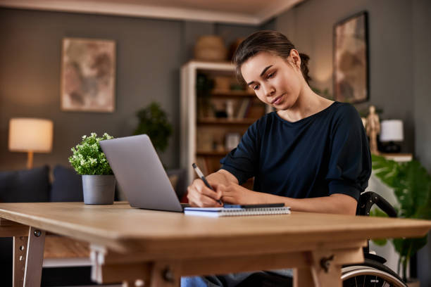 A lady who uses a wheelchair is documenting some thoughts while working from home.