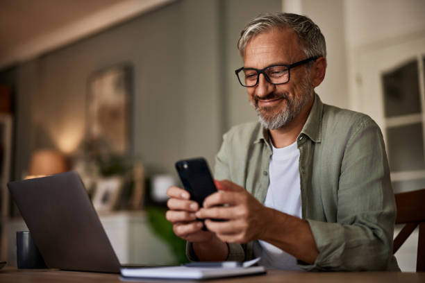 istock A mature male freelancer texting messages on a mobile phone while working on a laptop. 1614430318