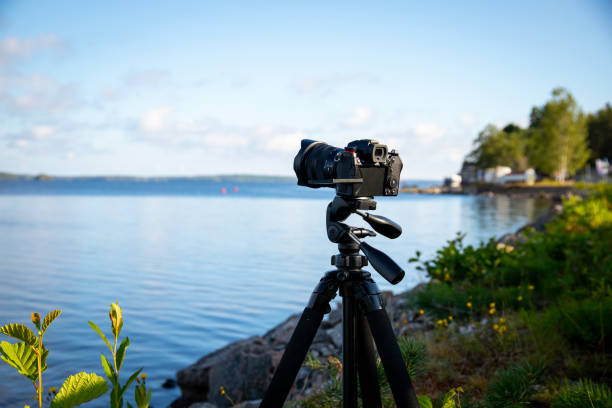 istock a camera mounted on tripod at beautiful lake scenery during day. blue sky and clouds on background. 1614430881