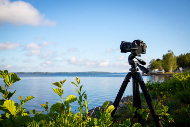 istock a camera mounted on tripod at beautiful lake scenery during day. blue sky and clouds on background. 1614431418