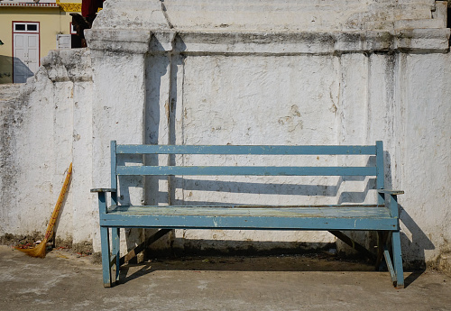 A vintage blue bench with old wall at sunny day in Mandalay, Myanmar.