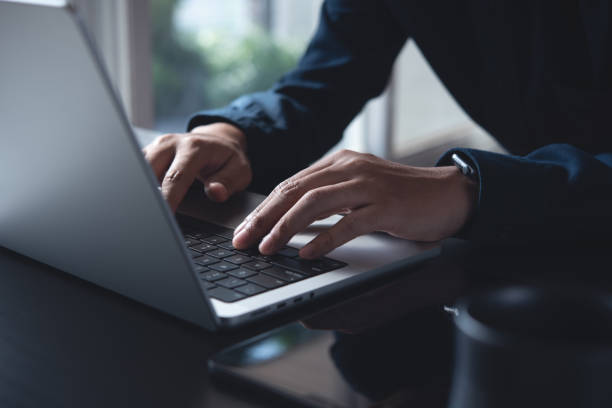 Business man hands typing on laptop computer keyboard, searching information, surfing the internet on dark office desk, distance job, online working, business and technology concept Business man hands typing on laptop computer keyboard, searching information, surfing the internet on dark office desk, distance job, online working, business and technology concept netbook stock pictures, royalty-free photos & images