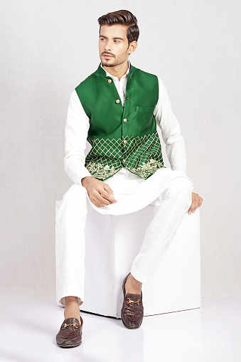 Pakistani Male Model posing in traditional green waistcoat with white kurta pajama