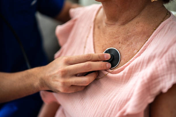 zbliżenie lekarza słuchającego bicia serca starszej kobiety - human cardiopulmonary system zdjęcia i obrazy z banku zdjęć