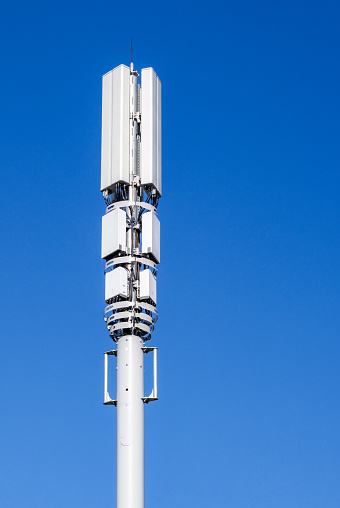 A close-up showing the telecommunications equipment on a 5G mast by a major city road.