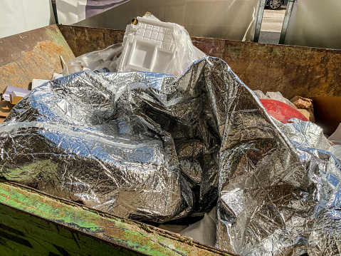 High angle view of crumpled aluminum sheet in garbage container in the street
