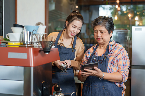 Asian female senior single mom Called my daughter to look at the online cash register, lots of drink orders coming in, beautiful Asian baristas. owner's daughter is happy and hugs her mother happily.