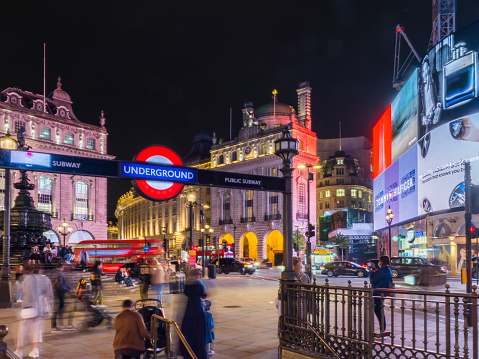 Iconic red London Bus passing by the popular tourist attraction Piccadilly Circus on Jan 2014.
