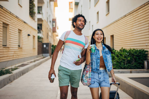 istock After leaving the accommodation where they stayed, two happy friends walk around town drinking coffee from a disposable cup 1614500691