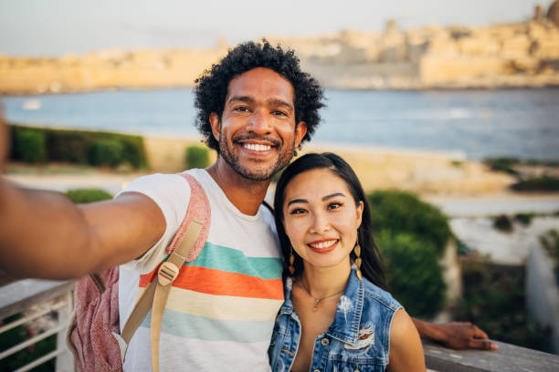 istock While standing on a dock not far from the sea, two smiling tourists take a selfie with a smartphone 1614503937