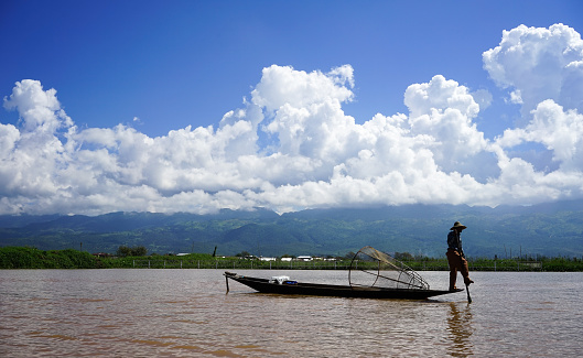 Shan, Myanmar - Oct 17, 2015. An Intha man fishing on Inle Lake at sunny day in Shan, Myanmar. Inle Lake is a freshwater lake located in the Nyaungshwe Township of Taunggyi District of Shan State.