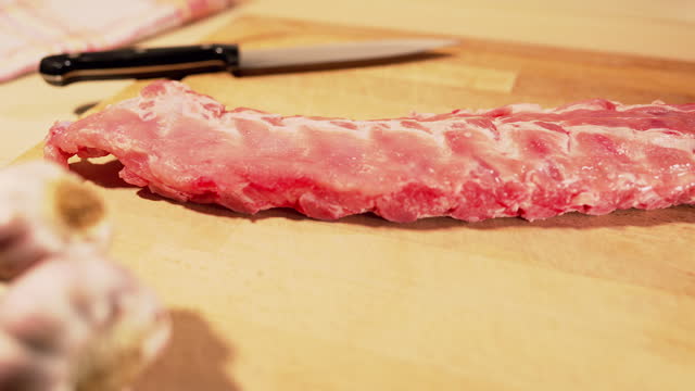 Rack of spareribs being placed on a wooden board