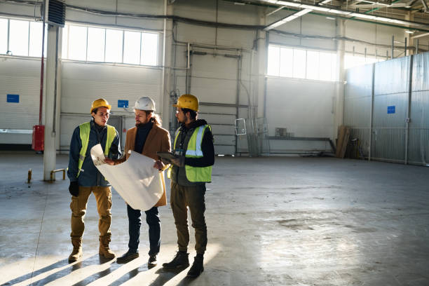 istock Long shot of two young multiethnic engineers and contractor with blueprint 1614564606