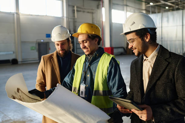 istock Side view of three young successful architects discussing points of sketch 1614565178