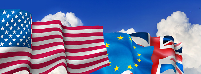 The image of the flags of the United States, the European Union and England fluttering in the wind against the background of a sky with white clouds