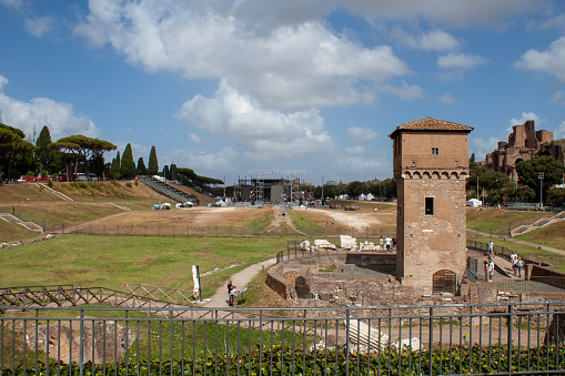Rome, Italy - August 06, 2023: View of the Circus Maximus set up for concerts and events, in the foreground the Torre della Moletta on a sunny day, people are present.