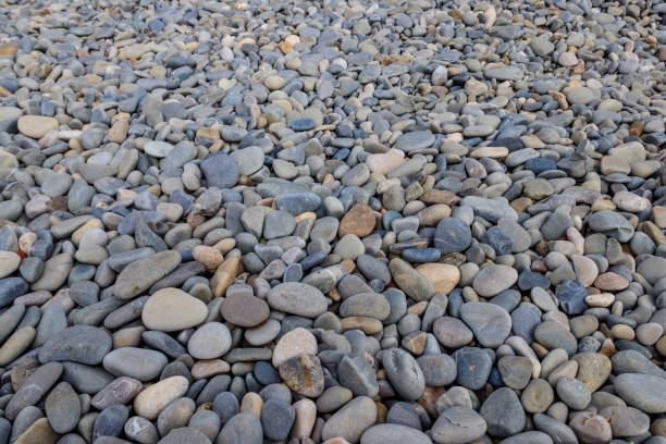 istock Smooth round pebbles texture background. Pebble sea beach close-up 1614577928