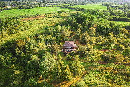 Aerial view of a rural, idyllic landscape with a village among agricultural fields and forests.