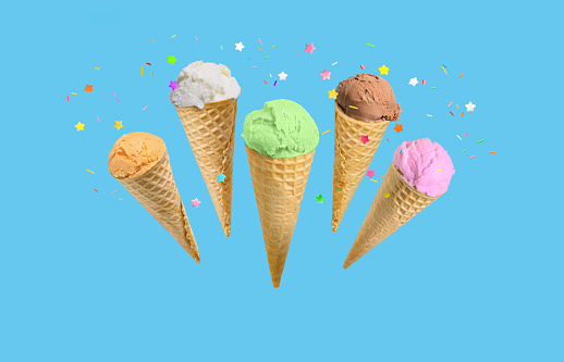 Ice cream scoops in waffle cones with sprinkles isolated on blue background. Birthday or holiday background