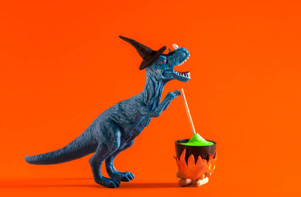 istock Blue dinosaur wearing witch hat is brewing potion in pot on orange background. Halloween greeting card. 1614652042