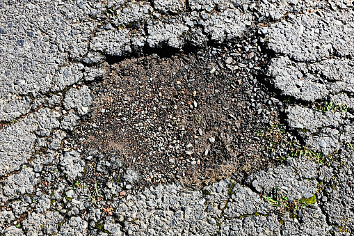 Damaged asphalt surface of a road, shot from directly above.