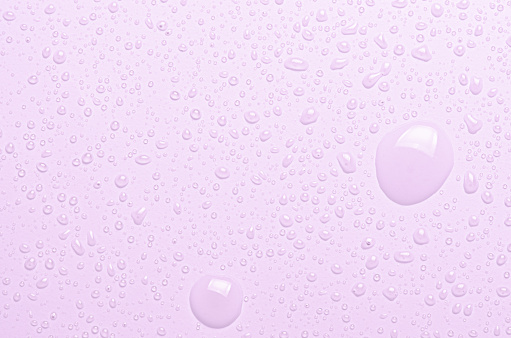 Drops of micellar water or cosmetic tonic on a pink background. Closeup, macro photography.