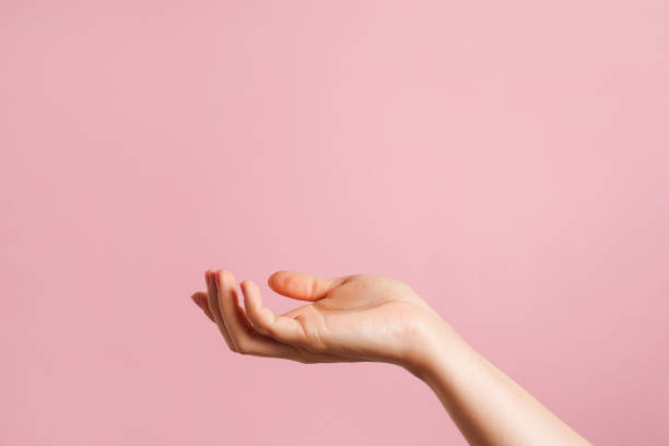 istock Hand open and ready to help or receive. hand as a podium for cosmetic products . pink background with copy space 1614671623