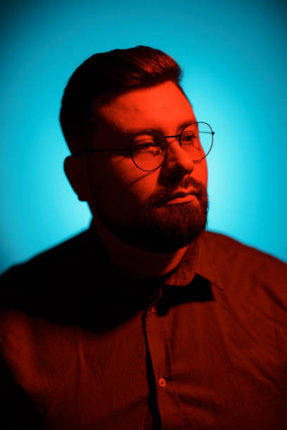 istock Serious man in eyeglasses looking at camera in neon light 1614700073