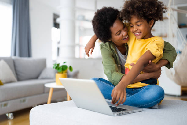 istock Affectionate caring mother and daughter hugging while using laptop in living room 1614730949