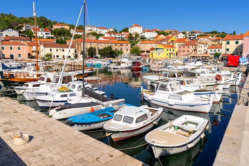 It is port of small town Saly on Long Island (Dolgi otok), what is in central Dalmatia coast not far from big Town Zadar on Croatian mainland. A lot of boats in water, car on pier and Centre of town in background.  Adriatic Sea as part of Mediterranean.