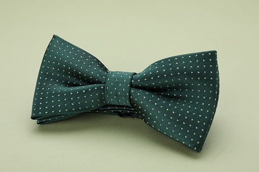 Stylish bow tie with polka dot pattern on pale green background, closeup