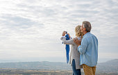 Mature couple pause above mountains and take photo