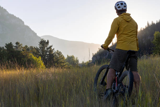 istock Mountain biker pauses in meadow at sunrise 1614757819
