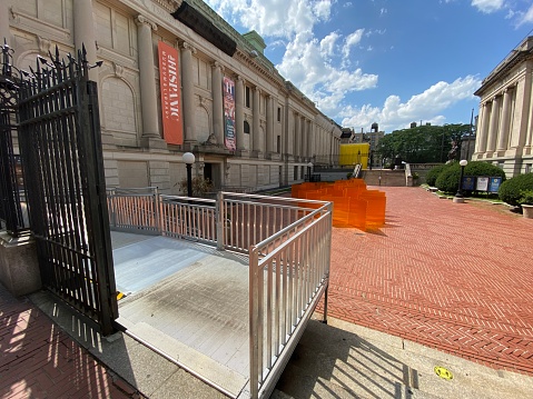 New York, NY USA - August 11, 2023 : View of the entrance to the modular metal ADA-compliant ramp for wheelchair users next to the steps at the front courtyard of The Hispanic Museum & Library in Washington Heights, New York City