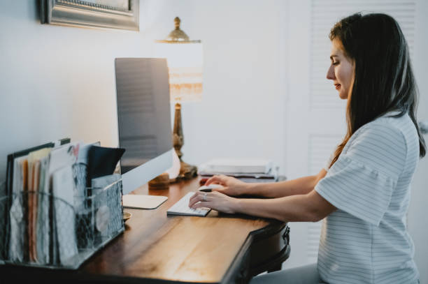 istock Woman works on desktop computer in a stylish home office indoors 1614797948