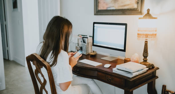 istock Woman works on desktop computer in a stylish home office indoors 1614798424