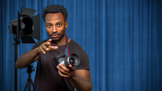 photographer studio work man holding camera in front of blue curtain professional shooting